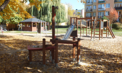 Zdjęcie przedstawia plac zabaw, z huśtawkami oraz altaną widoczną w tle