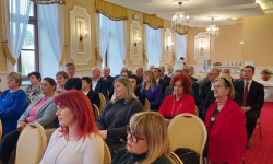 Konferencja LGD. Hrubieszów. Kobiety i mężczyźni siedzą  na krzesłach d dużej sali. 
