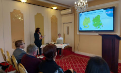 Konferencja LGD. Hrubieszów. W sali kobieta przemawia do zebranych osób. Za nią ekran z prezentacją. 