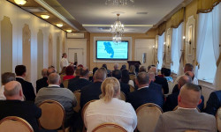 Konferencja LGD. Hrubieszów. Kobiety i mężczyźni siedzą  na krzesłach d dużej sali. 
