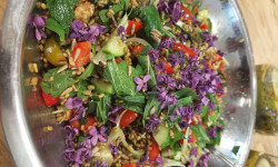 metalowa, okrągła miska z sałatką z cukinii, marchewki, zielonych liści udekorowanej kwiatami bzu lilaka 