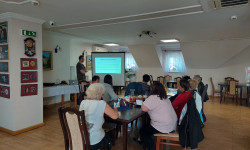 W sali przy stole siedzą osoby biorące udział w szkoleniu